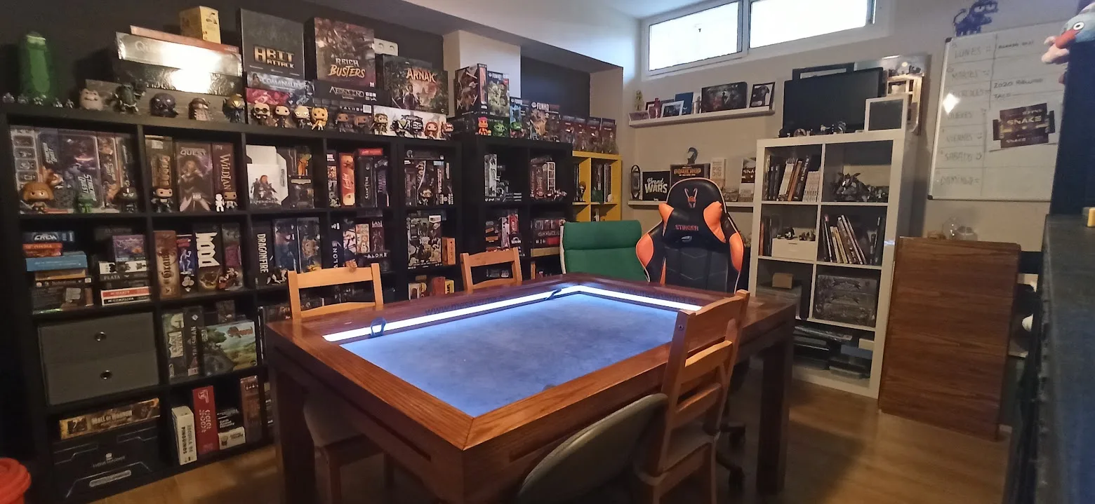 Mesa de juego con luz LED y estanterías de juegos de mesa en el estudio Tempus Fugit